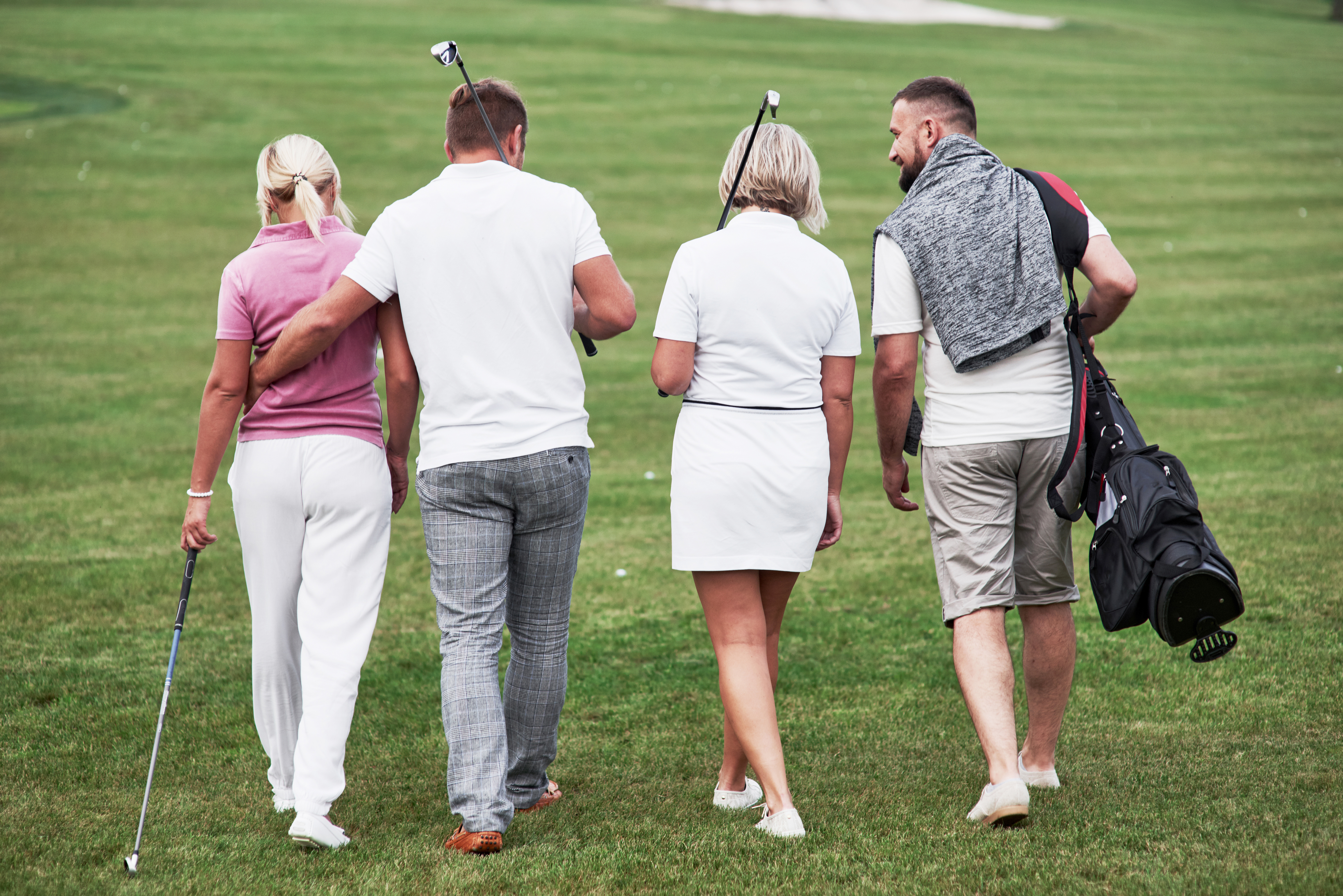picture of 4 friends walking together on a golf course